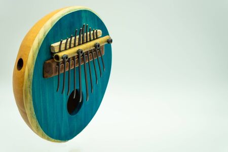 Standing view of a blue African kalimba on a white background with space on the right for text. Traditional music concept.の写真素材