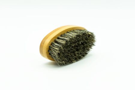 View of a bamboo beard brush with natural bristles lying on a white background Concept of facial...
