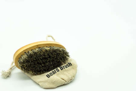Beard brush with natural bristles, on its case located on the left of the image with white background with space on the right. Concept facial care for men.の写真素材