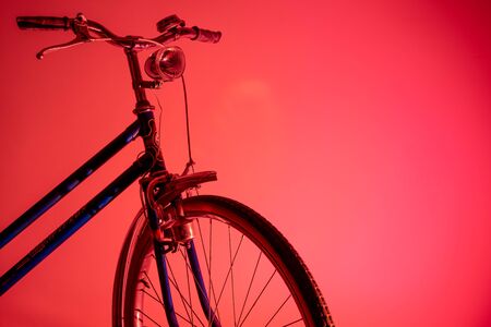 Old bicycle in shadow with isolated front light in colored background. Old bike concept.の写真素材