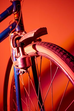 Front wheel of antique bike isolated in colored background. Vintage concept. Neon lights.の写真素材