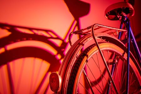 View of the back of an old isolated bicycle on a coloured background. Vintage concept. Neon lights.の写真素材
