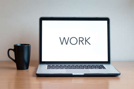 Laptop and a cup in a wooden table.の写真素材