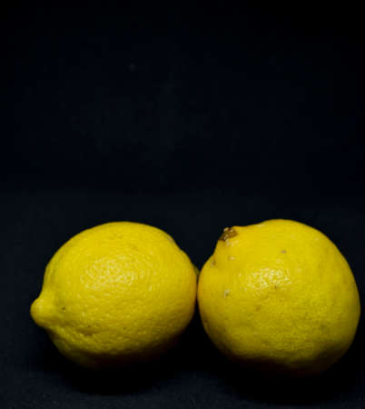Whole lemons on black background. Food with vitamin cの写真素材