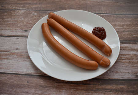 Sausages with ketchup on white plateの写真素材