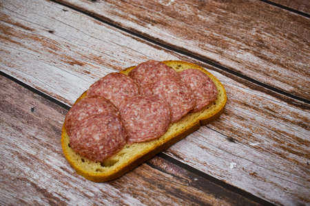 Salami on bread on wooden table. Poor foodの写真素材