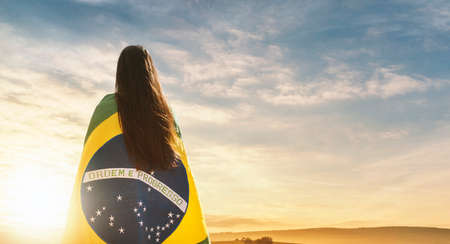 Woman with Brazilian flag on her back looking at the horizonの写真素材