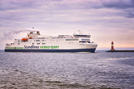 You see a big ferry going into the harbor of Warnemünde when it passes a small lighthouse.のeditorial素材