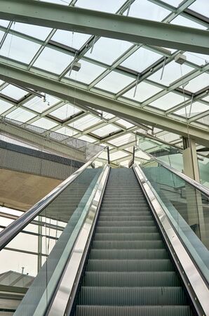 Escalator under a large glass roof.