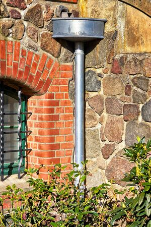 Old antique downpipe at a natural stone wall.
