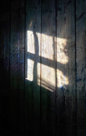 Light shines through a window on the wooden wall background.の写真素材