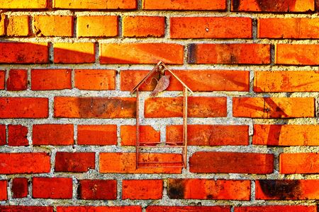 Old red brick wall with rusty metal decoration as background.