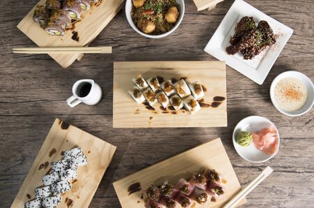Japanese sushi set. Sashimi, maki rolls and green tea. On plate over wooden background with space...