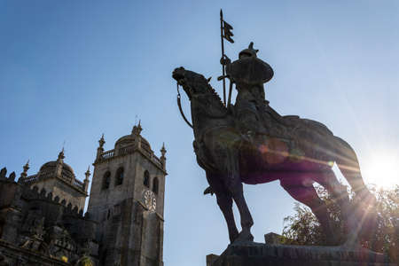 Warrior statue and Porto cathedral, Portugal. Sun peeking through the trees and lens flareの写真素材