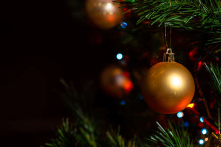 Golden Christmas ball in the tree and Christmas lightsの写真素材
