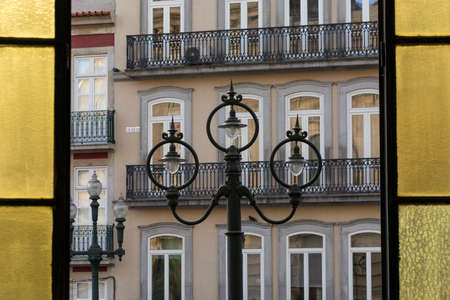 Vintage old street lamp, with buildings in the background. Yellow windows. Porto.の写真素材