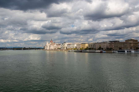 The hungarian Parliament in Budapest. Danube river with boats. Cloudy sky.の写真素材