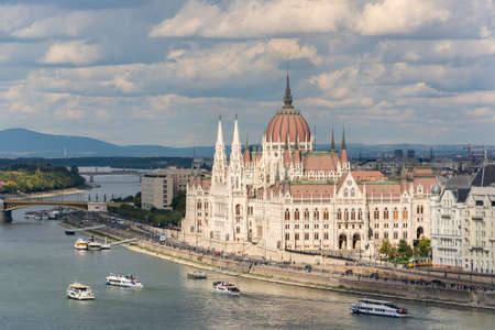 The hungarian Parliament in Budapest. Danube river with boats. Cloudy sky.の写真素材