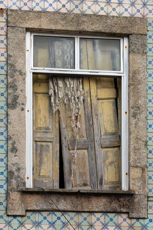 Old wood window half open. Stone frames. Blue portuguese tiles.の写真素材