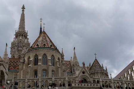 St. Matthias Church in Budapest, Hungary. Cloudy sky. Green trees.のeditorial素材