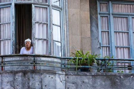 Old lady standing at the window, looking outside , Porto, Portugalのeditorial素材