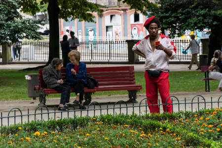 Artist guy dressed in red and white using the smartphone. Two ladies talking in the background. City of Portoのeditorial素材