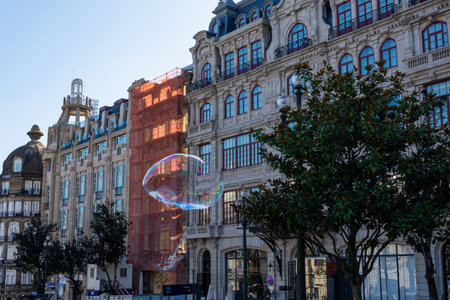 Porto, Portugal - 08/28/2019: Big soap bubbles and Porto city in the background. Aliados Avenue. Blue sky.の写真素材