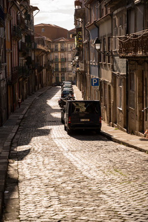 Picturesque street with old buildings in Porto and vehicles parked. Traditional Portuguese architecture. Warm light. Porto, Portugal.のeditorial素材