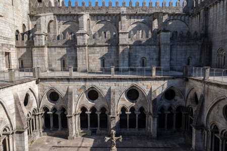 Porto cathedral seen from the inner courtyard. Old cross made of stone in the middle. Building made of stone. Porto, Portugal.の写真素材