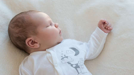 Newborn baby sleeping on blanket satisfied.