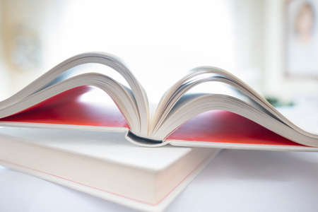 Shallow focus on open book in home environment. Focus on spine of book. Unfocused home environmentの写真素材