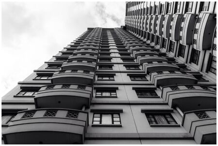 A picture of a high apartment building in Jakarta, Indonesia. Shot under a bright sky from below to...