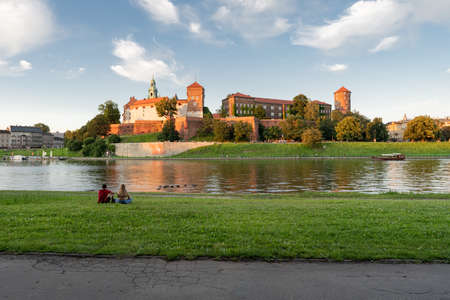 Woman and man sitting across from Wavel Castle in Cracowのeditorial素材