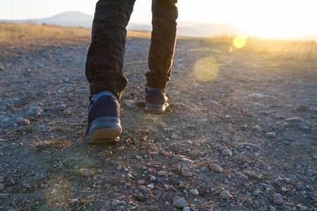 Close up of two feet with shoes are hiking on a stony way