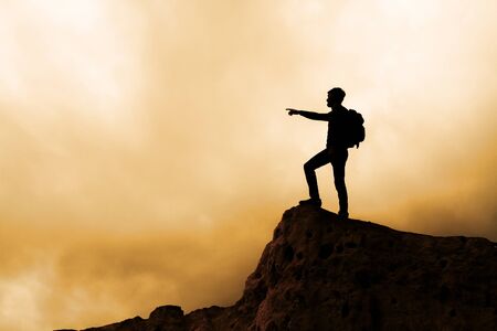 Silhouette of man standing on the top of mountainの写真素材