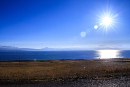 landscape with descending shore and blue surface of the lake and sky.