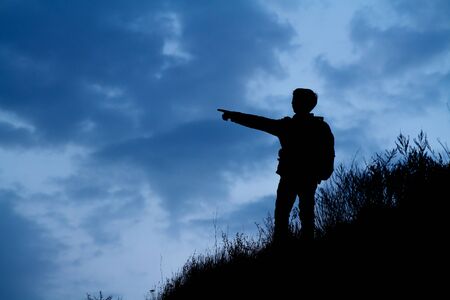 silhouette of man pointing against a blue skyの写真素材