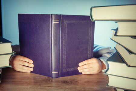 Hands cover her the face with a book.の写真素材