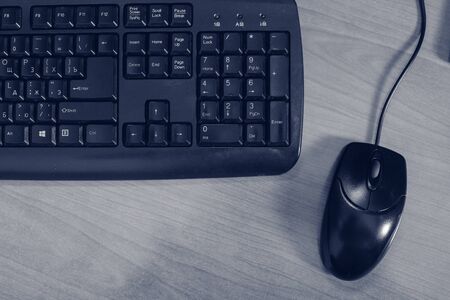 Black computer keyboard and mouse on a desk.