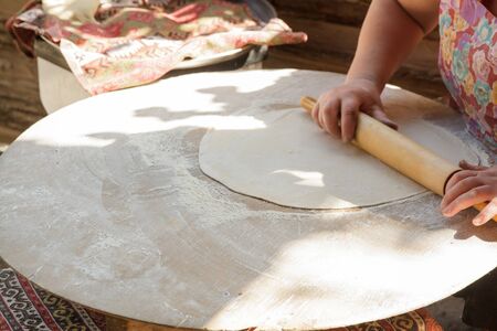 Roll out dough with rolling pin and flour on a wooden surfaceの写真素材