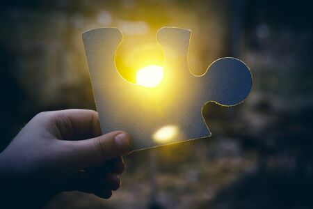 A hand holding a jigsaw pieceの写真素材