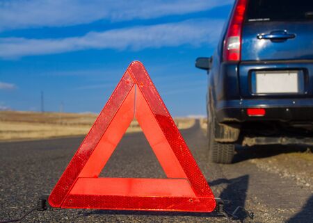 Red emergency stop sign and broken car on the roadの写真素材