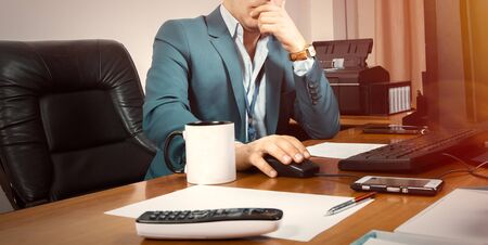 A businessman working on computer with a cup of tea and telephoneの写真素材