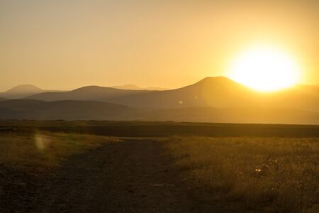 Sun shining over road, path, walkway through fieldの写真素材