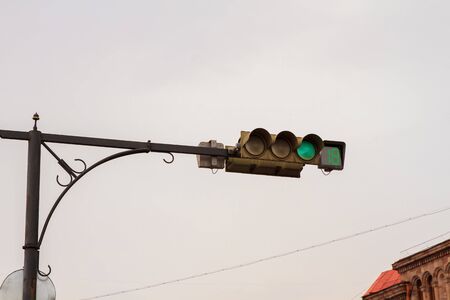 Green traffic light against grey skyの写真素材