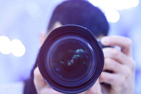 The man covers his face with the camera's lens.