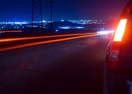 A car and blurred cars light trails in downtown night street. 