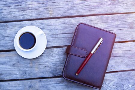 Coffee, pen and leather notebook on wooden background の写真素材