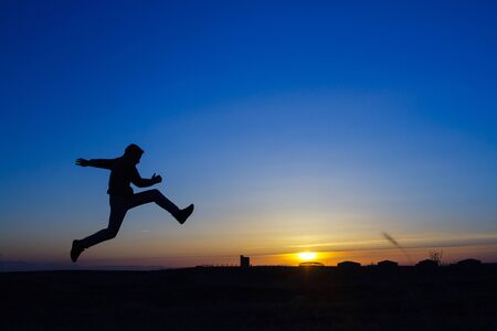 Silhouette of a man running on meadowの写真素材