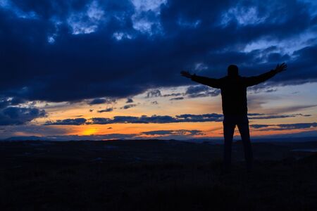 Man with raised-up arms at the beautiful sunset